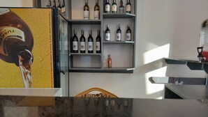 A bar area with shelves of wine bottles and a counter with a glass.