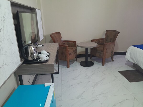 A hotel room with a bed, a small round table with chairs, a coffee maker, and a blue cabinet.