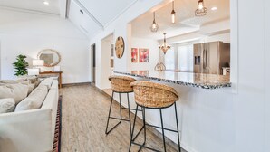 Een moderne keuken met een groot eiland, barkrukken, hanglampen en een koelkast.