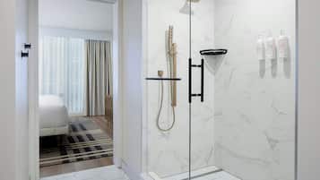 Une salle de bain moderne avec une douche à parois de verre, des carreaux de marbre et un porte-serviettes noir.