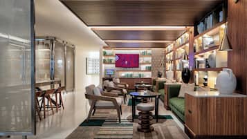 A modern living room with a wooden ceiling, a green sofa, a coffee table, and a bookshelf filled with books and decorative items.