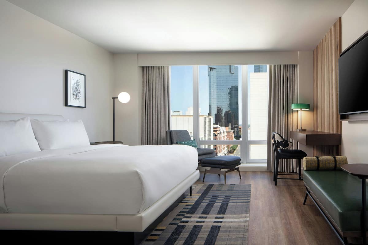 Hotelkamer met een groot bed, een bank, een televisie en uitzicht op de stad.