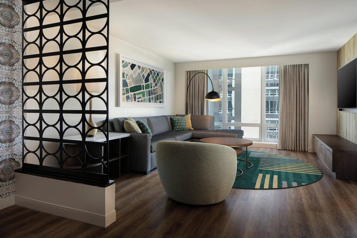 Een moderne woonkamer met een hoekbank, een rond bijzettafeltje en een decoratief vloerkleed.