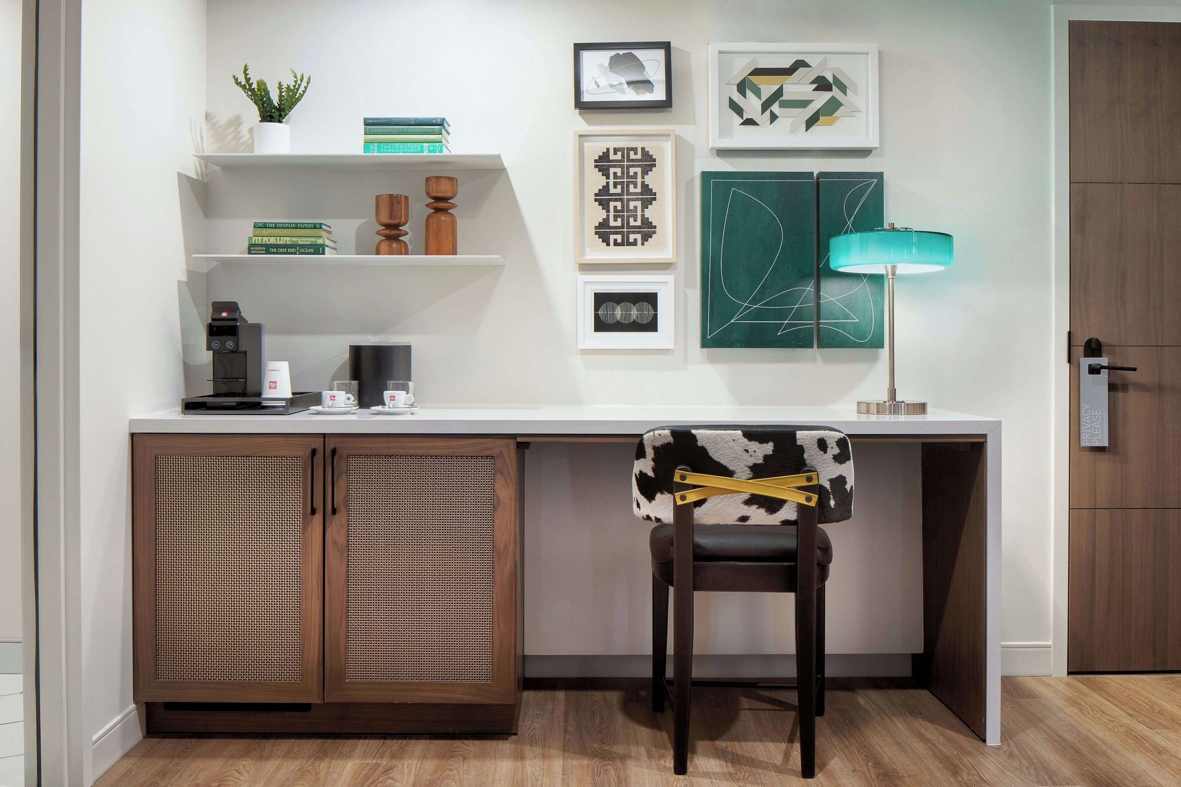 A modern kitchen with a white countertop, wooden cabinets, a coffee machine, and a chair with a cowhide pattern.