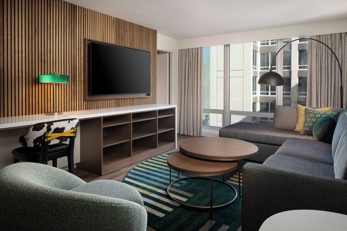Een moderne woonkamer met een flatscreen televisie, een bank, een salontafel en een tv-meubel met planken.