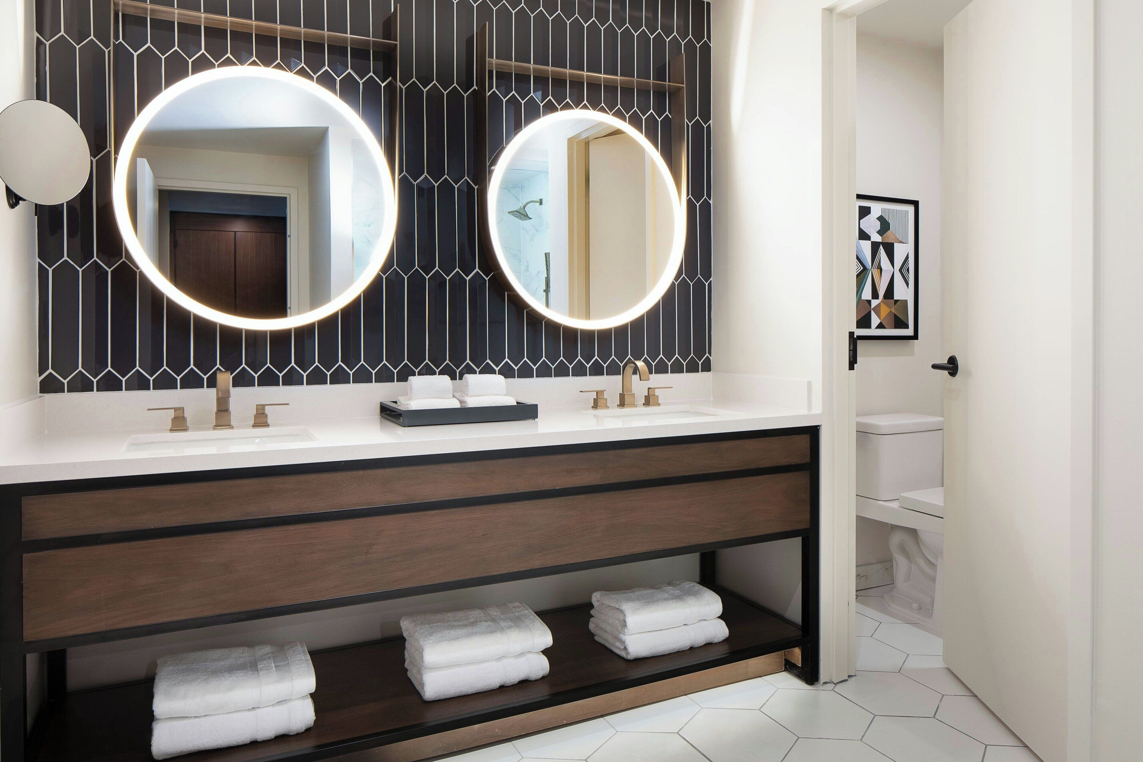 Un baño moderno con dos lavamanos, un espejo grande y un perchero para toallas.