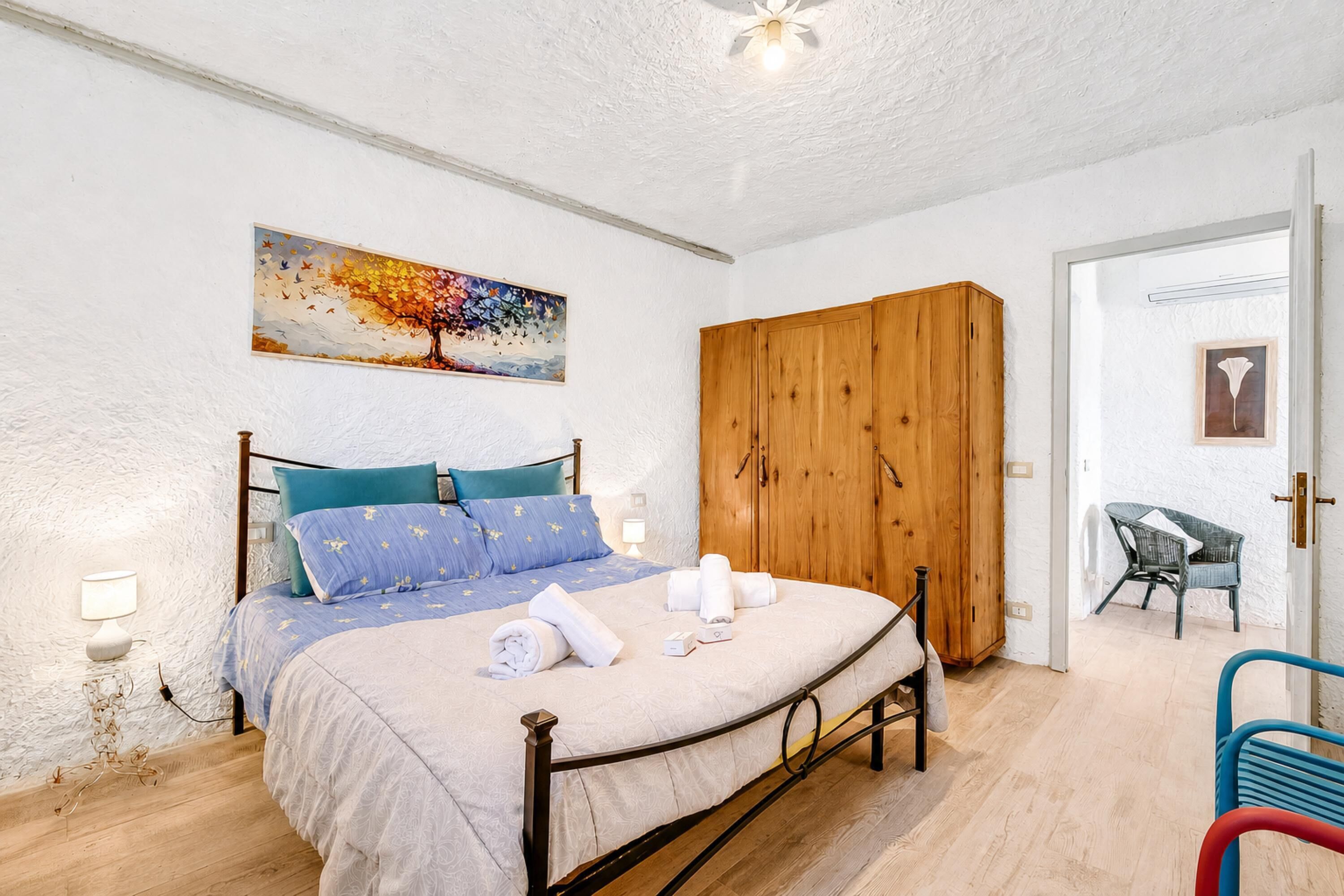 Une chambre à coucher avec un lit, une armoire en bois et un tableau accroché au mur.