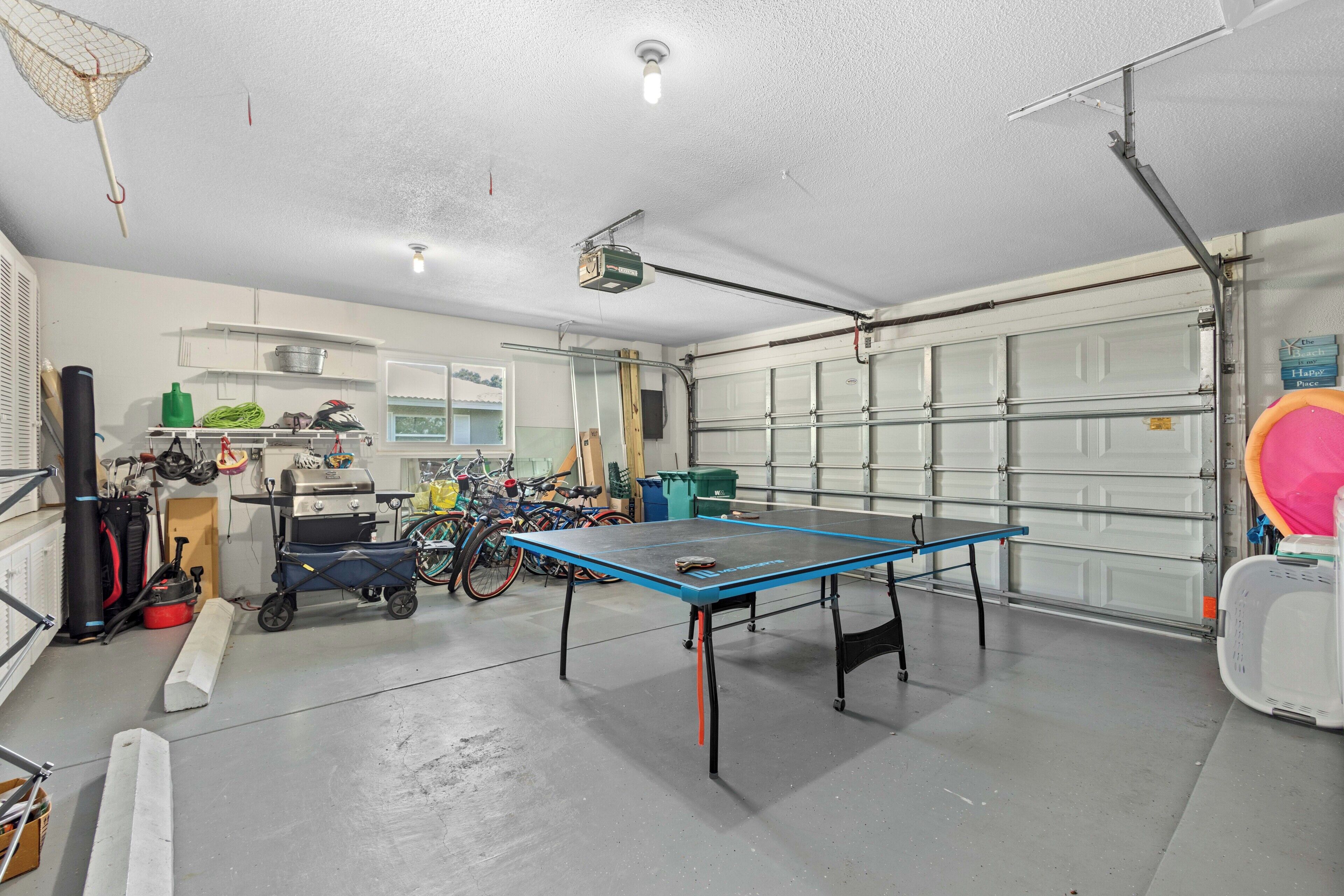 A garage with a ping pong table, bicycles, and various tools.
