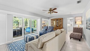 A living room with a sofa, ottoman, and a ceiling fan. - Tropical Escape–Private Pool Home Near the Sand Hy Tee on Longboat Key by RVA (Longboat Key)