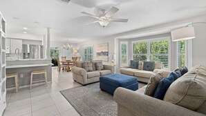 A modern living room with a sofa, ottoman, and a dining area with a table and chairs. - Tropical Escape–Private Pool Home Near the Sand Hy Tee on Longboat Key by RVA (Longboat Key)