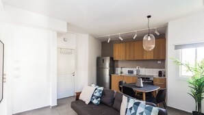 Una cocina moderna con armarios de madera, un refrigerador de acero inoxidable y una zona de comedor con mesa y sillas.