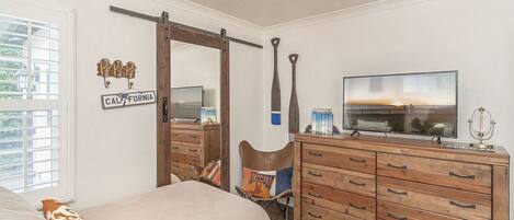 Een slaapkamer met een bed, een kaptafel en een televisie.