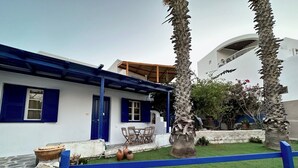 A white building with blue shutters and a covered patio area. - Naousa Getaway 2 Bd Dreamy Island Escape (Paros)