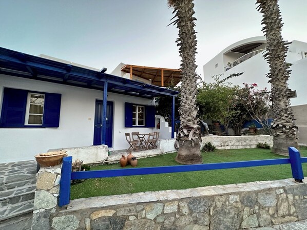 A white building with blue shutters and a covered patio area.