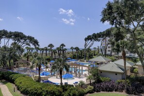 A resort with a pool area, palm trees, and a view of the ocean.