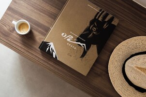 Un libro, una taza de café y un sombrero de paja sobre una mesa de madera.