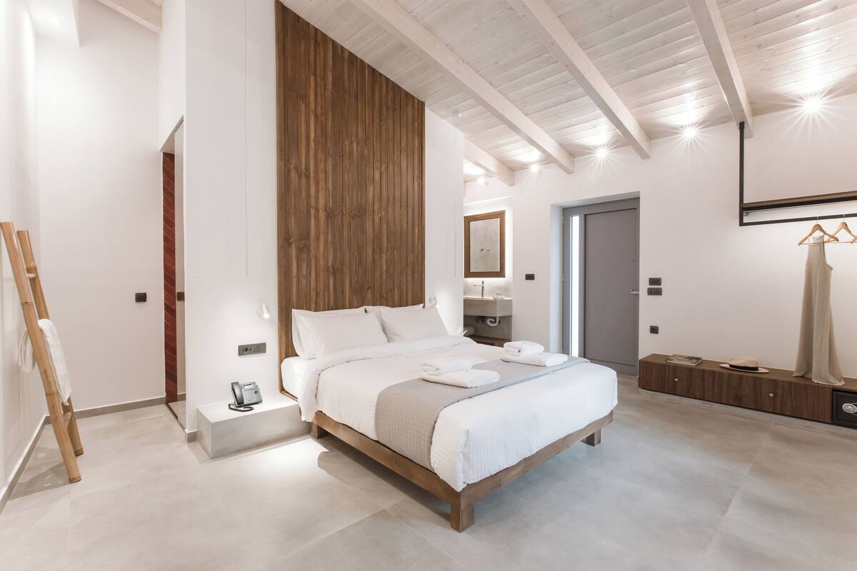 A modern bedroom with a wooden bed frame, a bedside table with a phone, and a hanging garment rack.