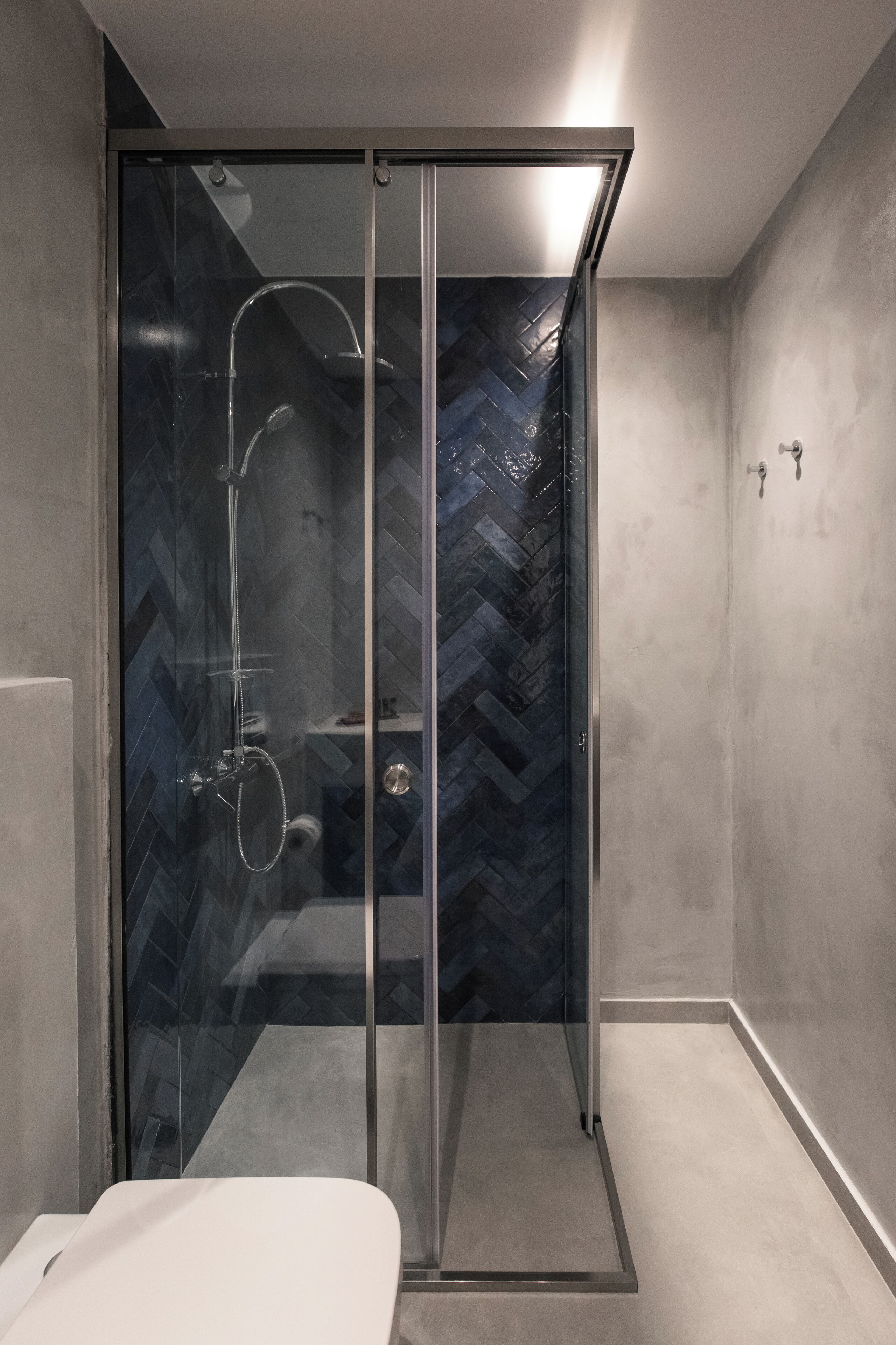 Une salle de bain moderne avec une douche à parois de verre, une baignoire blanche et un pare-baignoire carrelé avec un motif en chevrons.