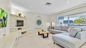 Un salon moderne avec une cheminée en pierre, une grande horloge, un canapé et un téléviseur.