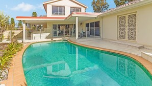 Une maison moderne dotée d’une piscine, d’un patio couvert et d’un portail décoratif.