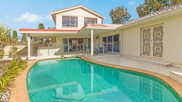 A modern house with a swimming pool, a covered patio, and a decorative gate.