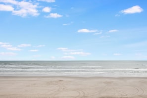 Una playa con cielo despejado y mar tranquilo.