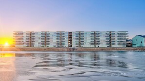Un hotel a più piani con balconi, situato vicino a una spiaggia e un mare tranquillo.