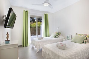 A bedroom with two beds, a flat-screen TV mounted on the wall, and a ceiling fan. - Villa Estanyol (Campos)
