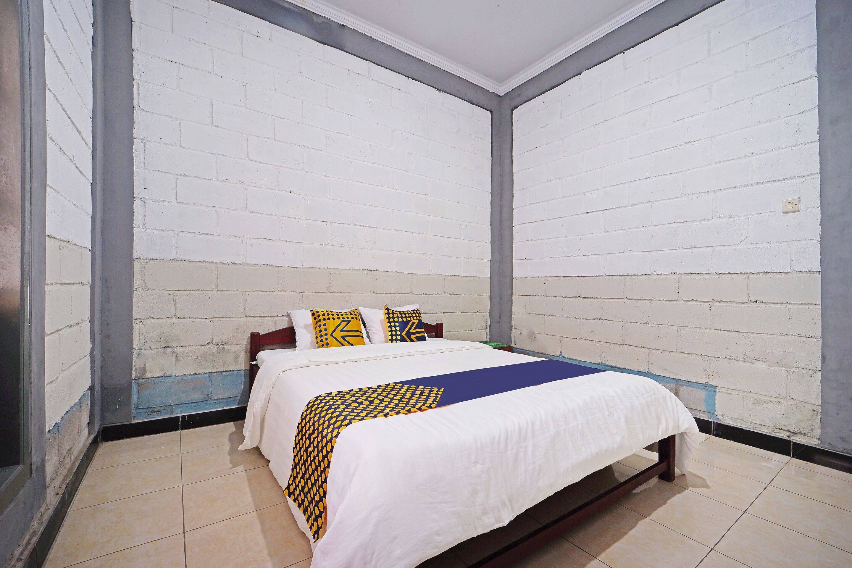 A room with a bed, white walls, and a tiled floor.