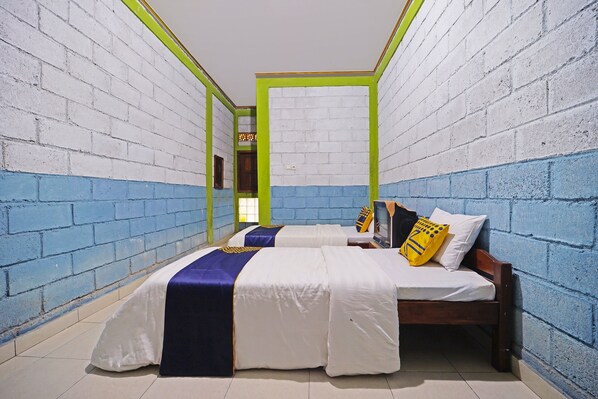 Una habitación con dos camas, paredes blancas y azules, y un espejo en una pared.