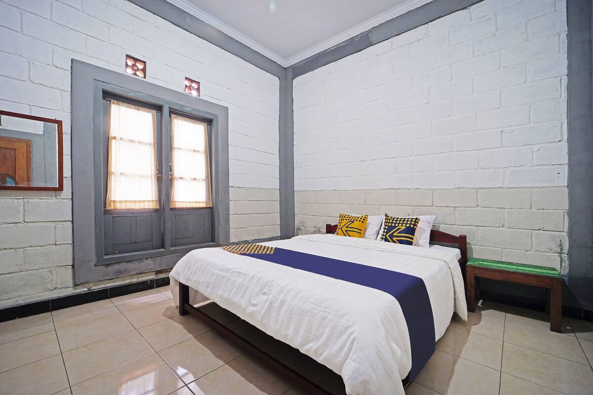 Une chambre à coucher avec un lit, une fenêtre et un cadre photo fixé au mur.