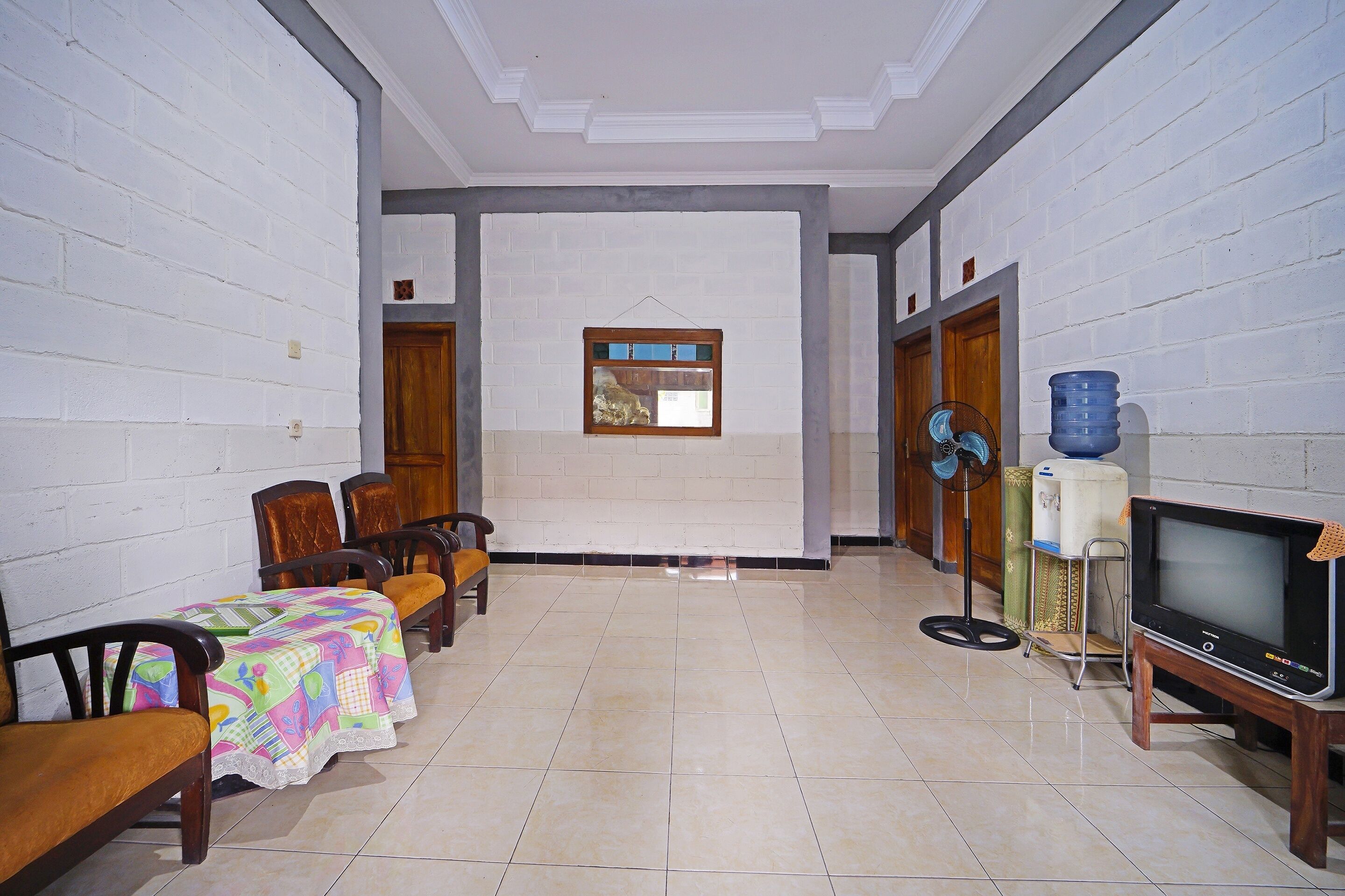 A dining area with a table set for four, chairs, a TV on a stand, and a water dispenser.