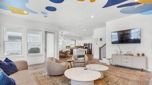 Una sala de estar moderna con un sofá, sillones, una mesa de centro y un televisor.
