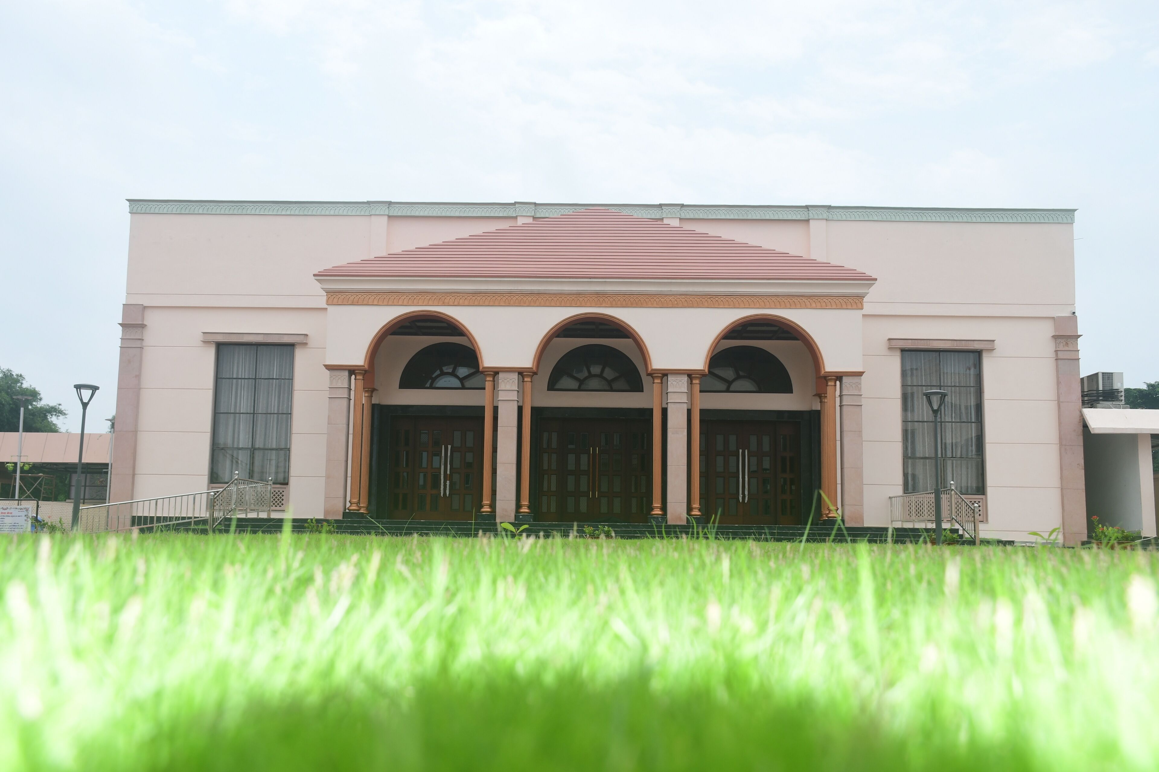 A building with a symmetrical facade, three arched doorways, and a flat roof.