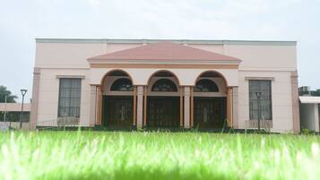A building with a symmetrical facade, three arched doorways, and a flat roof.