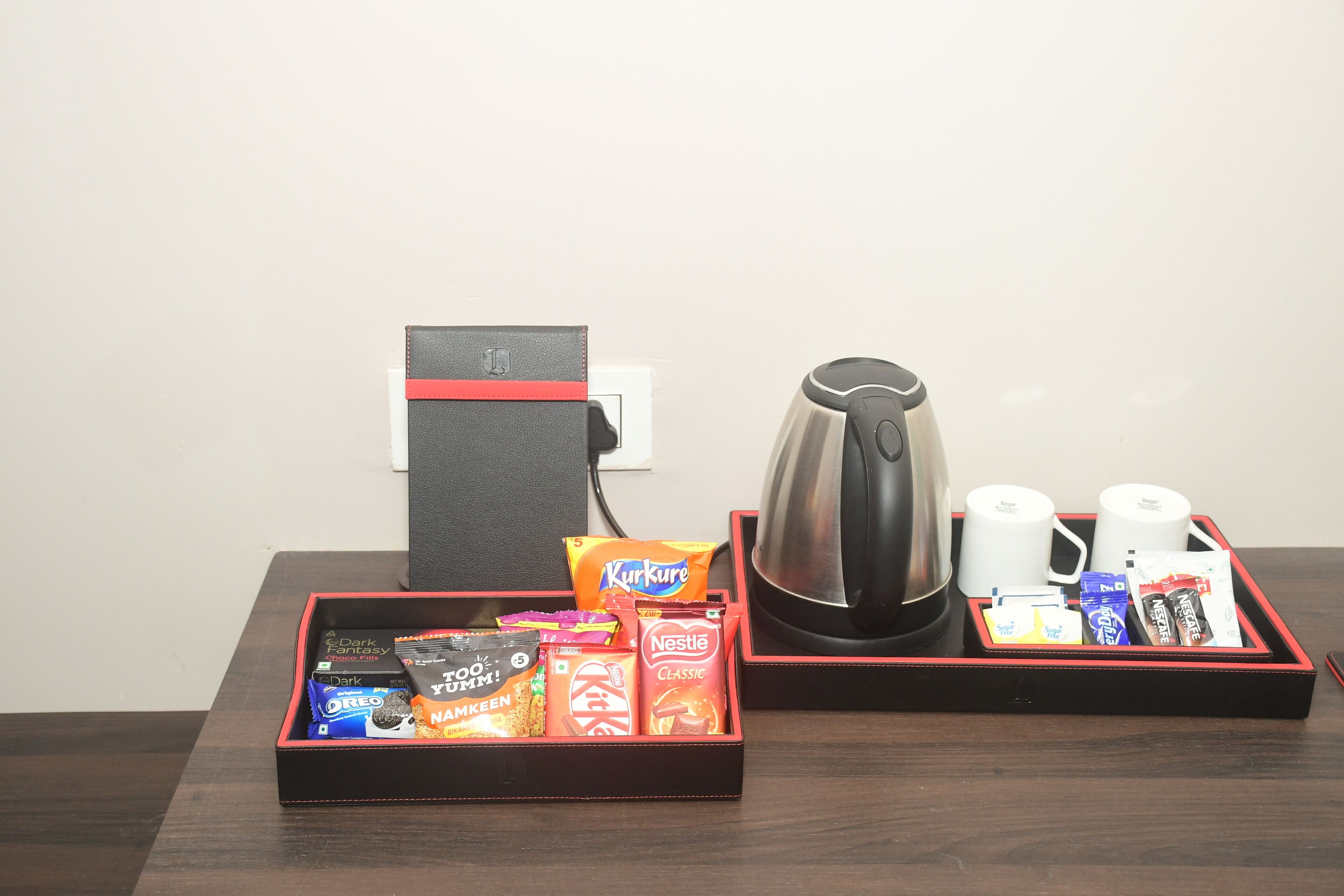 A hotel room with a breakfast tray containing assorted snacks, a coffee maker, and a kettle.