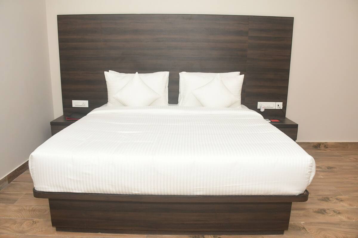 A neatly made bed with a dark headboard, white bedding, and two bedside tables with lamps.