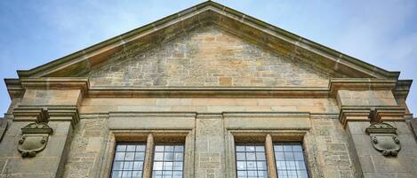 A building with a triangular pediment, rectangular windows, and stone carvings.