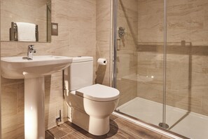 A bathroom with a sink, toilet, and glass-enclosed shower. - The Foal (Hexham)