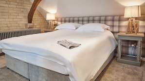 Une chambre avec un grand lit, deux lampes de chevet, un mur en briques et un plafond en pente.
