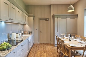 Una cocina con armarios blancos, encimera de granito y comedor con mesa de madera para seis personas.
