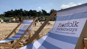 Cadeiras de praia com um letreiro anunciando 'Norfolk hideaways: refúgios de férias na costa e no campo'.