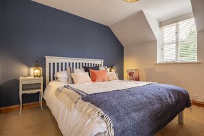 A bedroom with a bed, nightstands, a window, and a lamp.