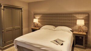 A hotel room with a large bed, two bedside tables with lamps, a wardrobe, and a plaid headboard. - The Stalls (Hexham)