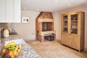 A kitchen with a brick fireplace, a granite countertop, and a wooden cabinet with glass doors.