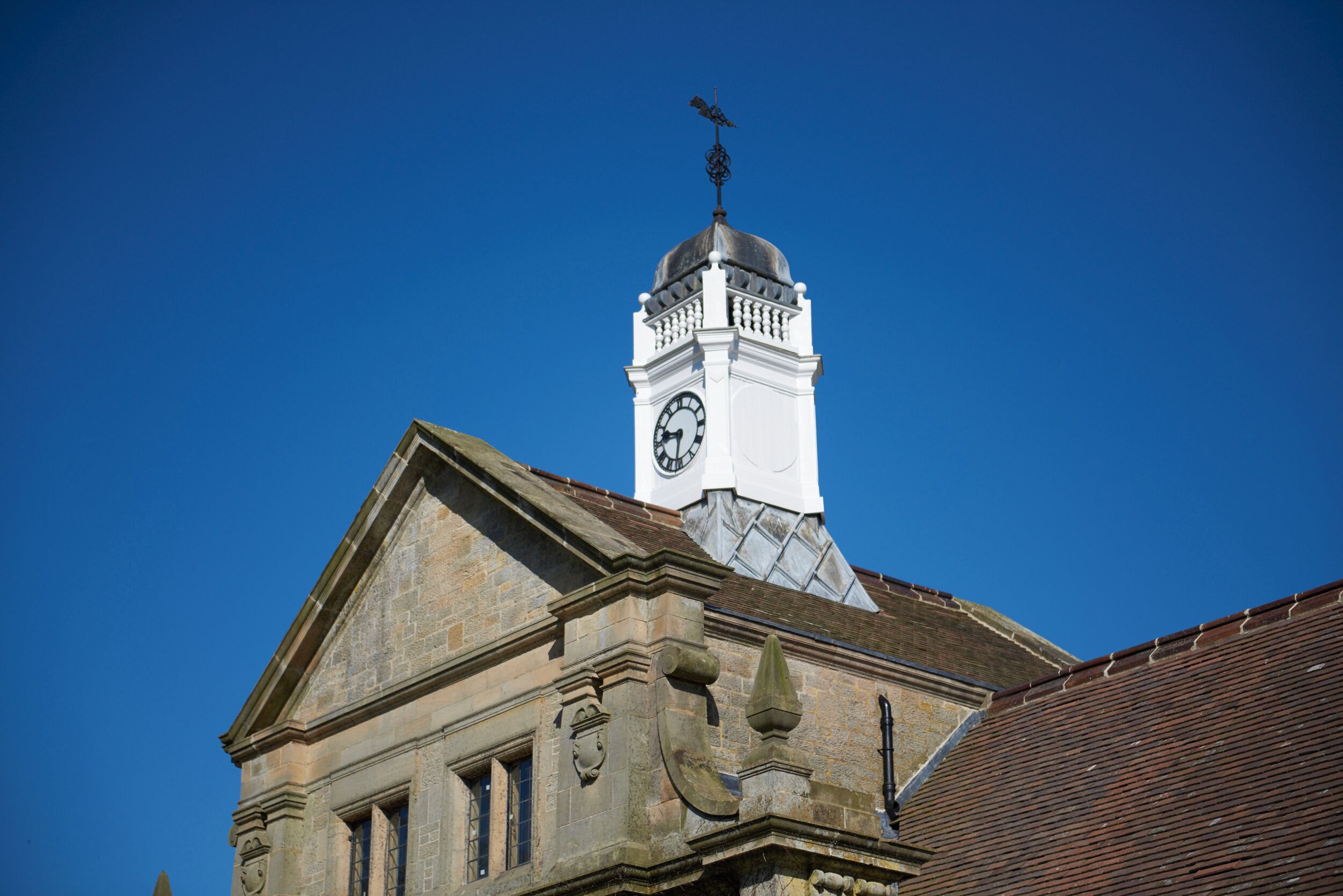 A historic building with a prominent clock tower and a weathervane.