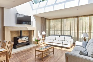 A modern living room with a fireplace, a sofa, a coffee table, and a TV mounted on the wall.