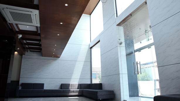 En moderne lobby med en modulopbygget sofa, marmorgulv og store vinduer, der lukker naturligt lys ind.