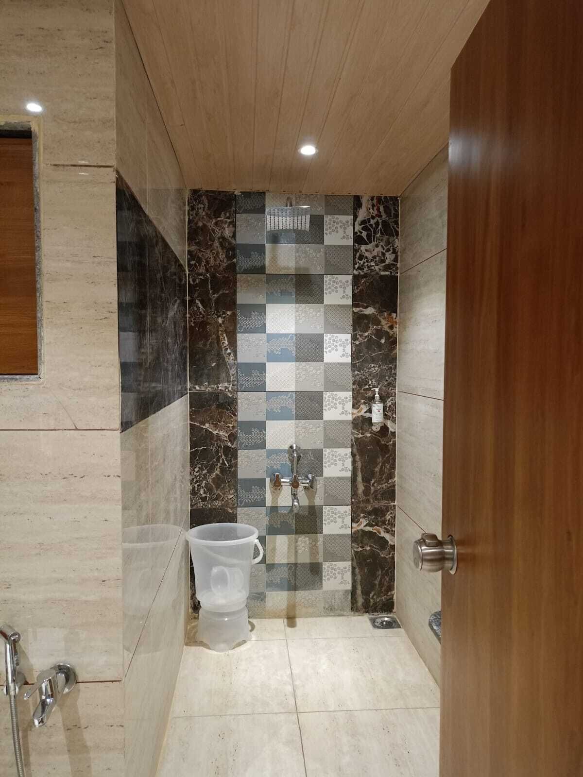 A bathroom with a checkered tile wall, a toilet, a shower, and a sink.