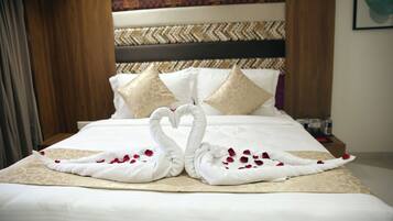 A bed with a decorative swan towel arrangement and rose petals.